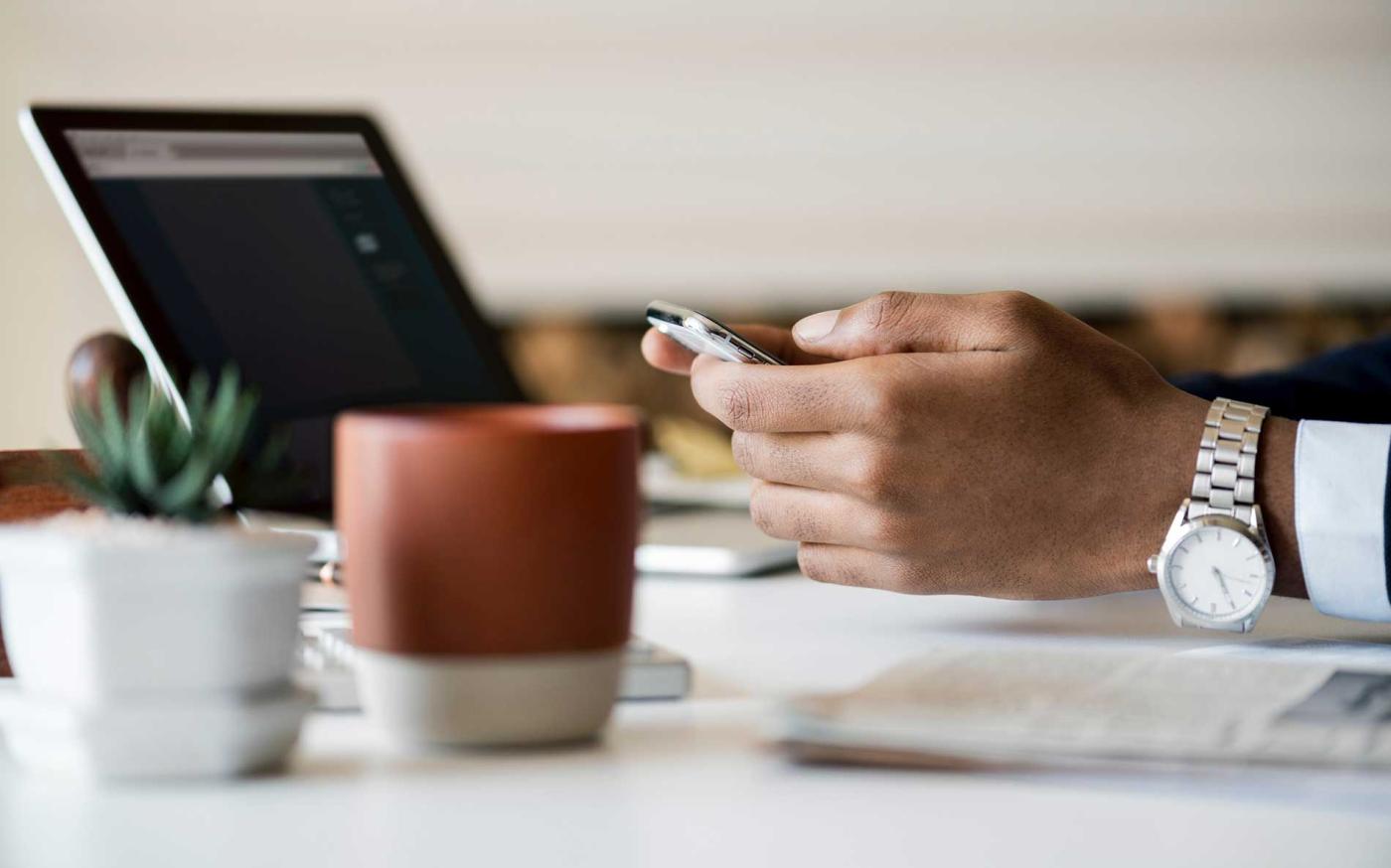 Hands with phone and laptop